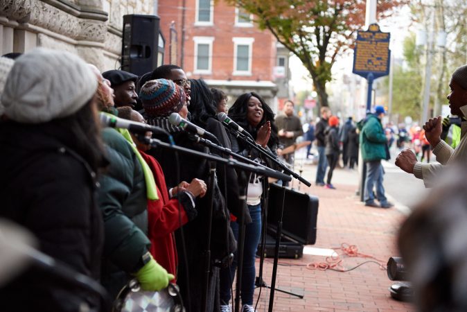 The Mother Bethel A.M.E. Church Choir lines up outside the church on the morning of Sunday, Nov. 18, 2018, and sings as participants of the Philadelphia Marathon run past. (Natalie Piserchio for WHYY)