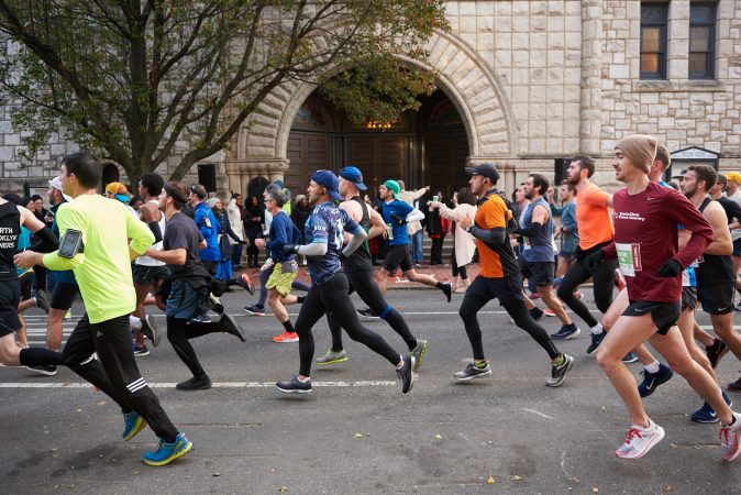 Participants of the 2018 Philadelphia Marathon run past Mother Bethel A.M.E. Church while members of the church sing on the front steps. (Natalie Piserchio for WHYY)