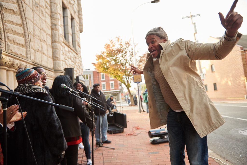 2018 18 11-n piserchio-reverend doctor mark tyler-mother bethel ame church 6th street old city society hill philadelphia pa-2018 philadelphia marathon choir Jonas Crenshaw, Jr. conducts the Mother Bethel A.M.E. Mass Choir outside the church, as participants of the 2018 Philadelphia Marathon run up Sixth Street, along their route. (Natalie Piserchio for WHYY)