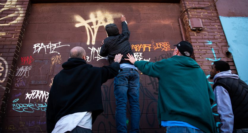 Graffiti writers tag a wall adjacent to a mural dedicated to the late graffiti writer Karaz on Saturday, November 3, 2018. (Kriston Jae Bethel for WHYY)