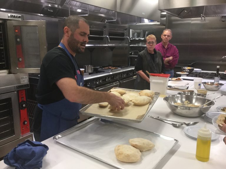 Ari Miller serves fresh pita bread to accompany hummus at the Culinary Literacy Center at the Central Parkway Free Library. (Kyrie Greenberg for WHYY)