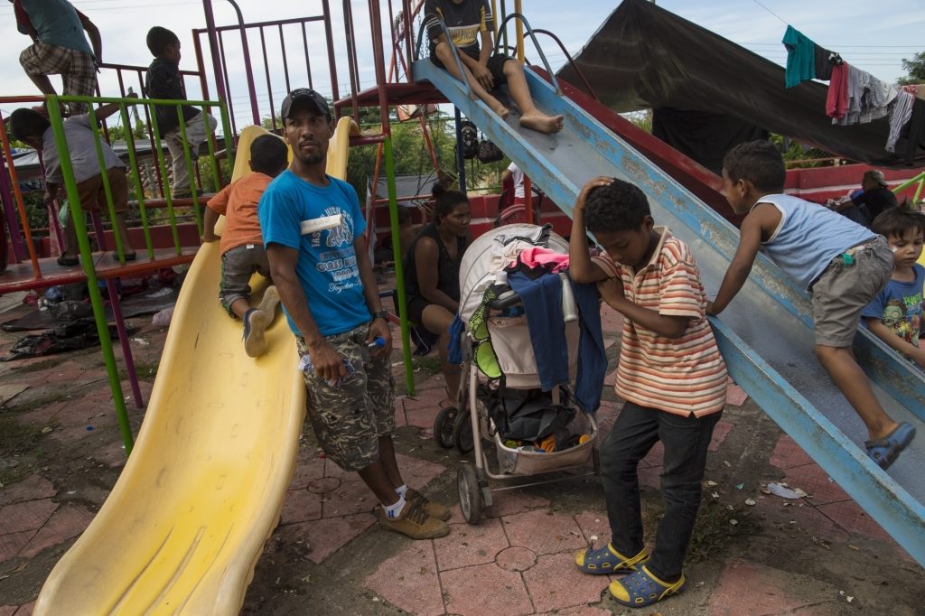 Mexico Migrant Caravan One Day Joel Eduardo Espinar, (left), and his son, Jason, 11, wait at their chosen campsite in the main square of Tapanatepec, Mexico, on Oct. 28, 2018. His plan is to request asylum rather than cross the U.S. border illegally.