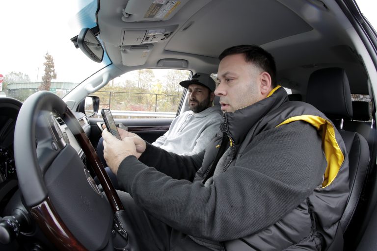 In a photo taken Friday, Nov. 9, 2018, in Bayonne, N.J., Lenny Sciascia, (right), and his friend Mario DeAngelis look at betting lines for the day's sporting events before placing bets in a parking lot just off the Bayonne Bridge, which divides New York and New Jersey. Sciascia, who lives in Staten Island, N.Y., commutes regularly to places his bets from New Jersey, where online betting is legal. With sports betting being advertised all around them but the opportunity to actually do it restricted to just one nearby state, gamblers from New York and Pennsylvania are crossing bridges and tunnels into New Jersey to make legal sports bets. (Julio Cortez/AP Photo)