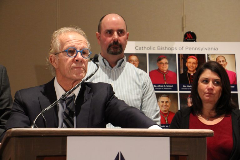 Attorney Jeff Anderson announces a suit against the Pennsylvania’s eight Catholic dioceses on behalf of victims of clergy child sexual abuse. He is joined by victim Daniel Hillanbrand and Hillanbrand’s wife, Donna. (Emma Lee/WHYY)
