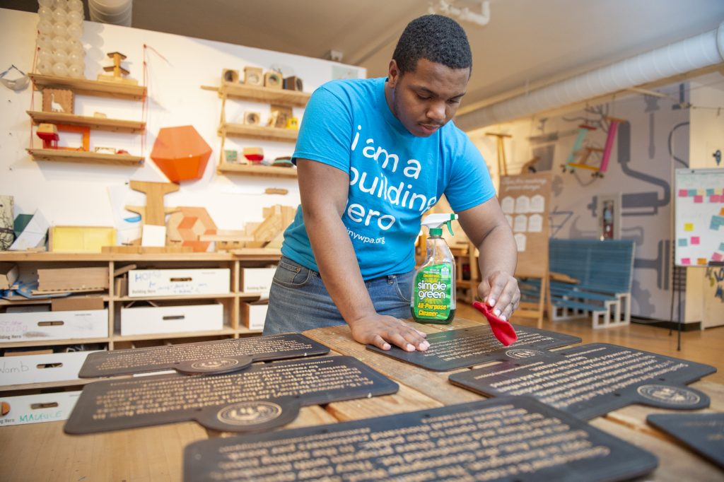 TINY WPA Najaye Davis cleans signs after they are cut by a laser cutter. (Jonathan Wilson for WHYY)