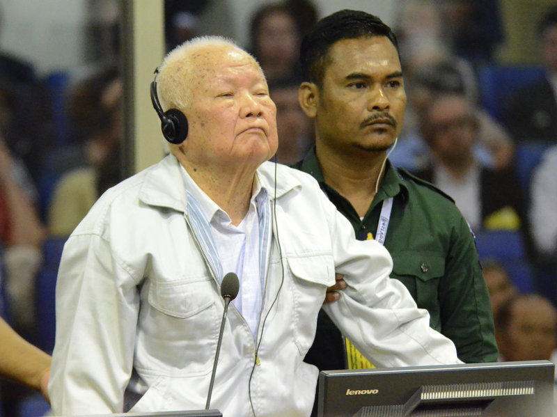 ap_18320194399800-ab211d4b2255e322ed5b90f6840d53f5d56a6ec3-s800-c85 Khieu Samphan, (left), former Khmer Rouge head of state, stands at the dock in a court room during a hearing at the U.N.-backed war crimes tribunal in Phnom Penh, Cambodia, on Friday. (Nhet Sok/AP/Extraordinary Chambers in the Courts of Cambodia)