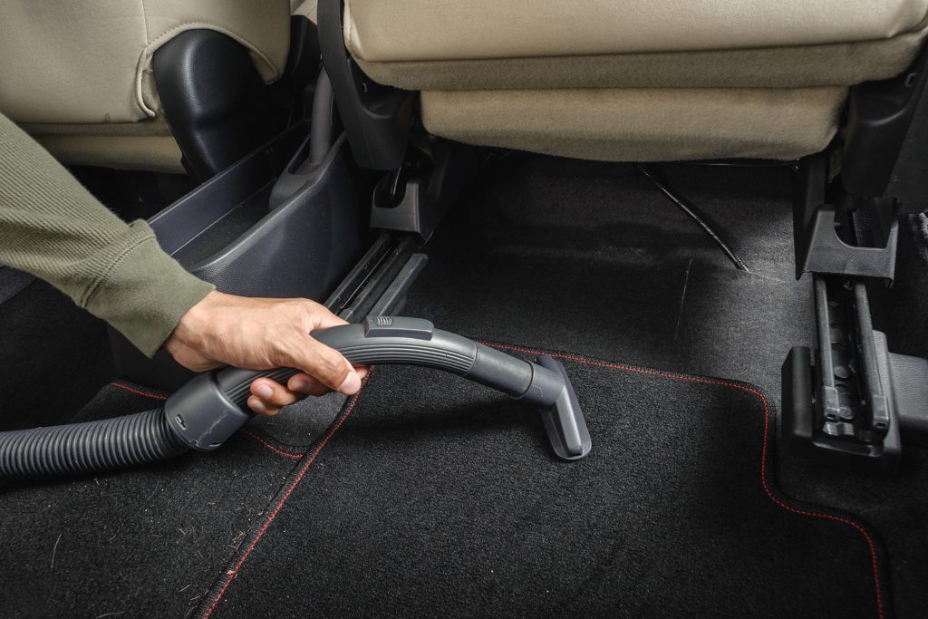 Cleaning A man cleans the carpet in his car with vacuum cleaner. (Bigstock Image)