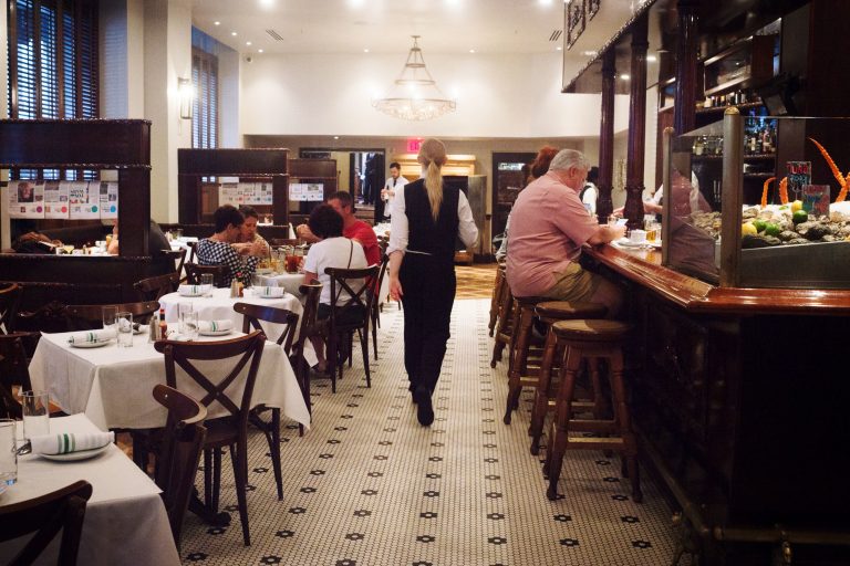 A member of the staff walks through Luke, one of the restaurants still owned by John Besh, on St. Charles Avenue in New Orleans. (Emily Kask for NPR)