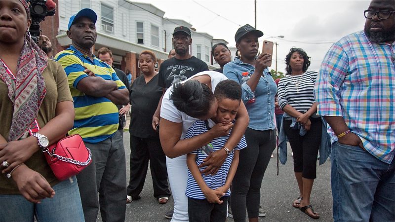 Sakinah Crew comforts her 7-year-old son, Swyhir, during a rally to seek justice for the death of Sandrea Williams. She was killed in a random act of gun violence outside of her mother’s home in West Philadelphia. Their teenage cousin was also injured by gunfire that night. (Emily Cohen for WHYY)
