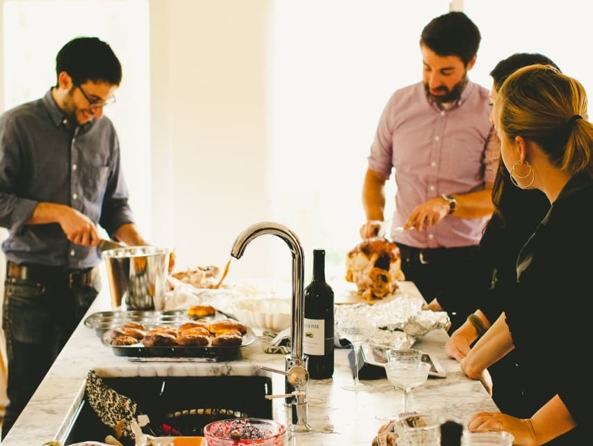 Michael Durand (left), husband of Kitchn Editor-In-Chief Faith Durand, and friend Chris Gardner (right) carve turkey while guests hang out in the Durands' kitchen at a recent party, dirty dishes and all. (Kitchn/Rachel Joy Barehl)
