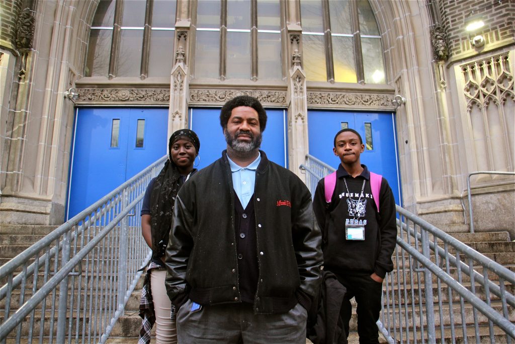 2018 03 01-e lee-sharif el mekki-philadelphia mastery shoemaker school-student activists Sharif El-Mekki, principal of Mastery Shoemaker Elementary in Philadelphia, founded a group that seeks to boost the number of black male educators. Here he stands at the entrance to the school with students Essi Gasonu (left) and Bryce Thompson.