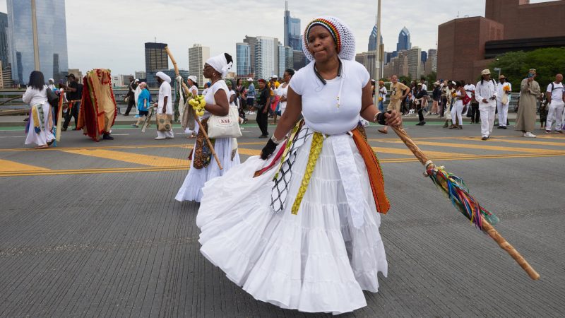 Yannie dances over the South Street Bridge before the procession to Oshun, the Goddess of the River, during the Odunde festival on June 10, 2018. (Natalie Piserchio for WHYY)