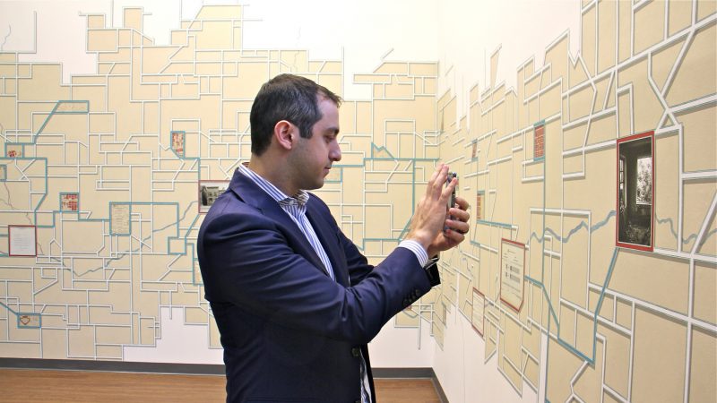A visitor to Philadelphia City Archives uses his phone to interact with Talia Greene's vast mural, 