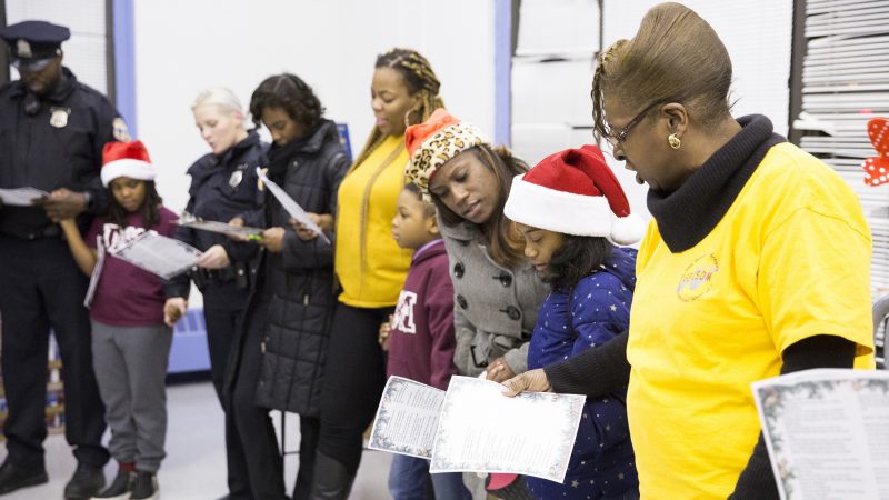 Joyce Drayton (right), the founder of the Georgia E. Gregory Interdenominational School Of Music, joins community members and police officers in holding hands and singing 