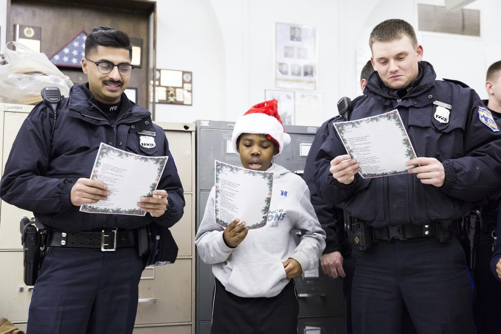 Officers Rana Ashfaq (left) and Joe Crouse flank Kofi Walker, 9, at the Caroling with a Cop event held in collaboration between the 39th Police District and the Georgia E. Gregory Interdenominational School Of Music on December 7.