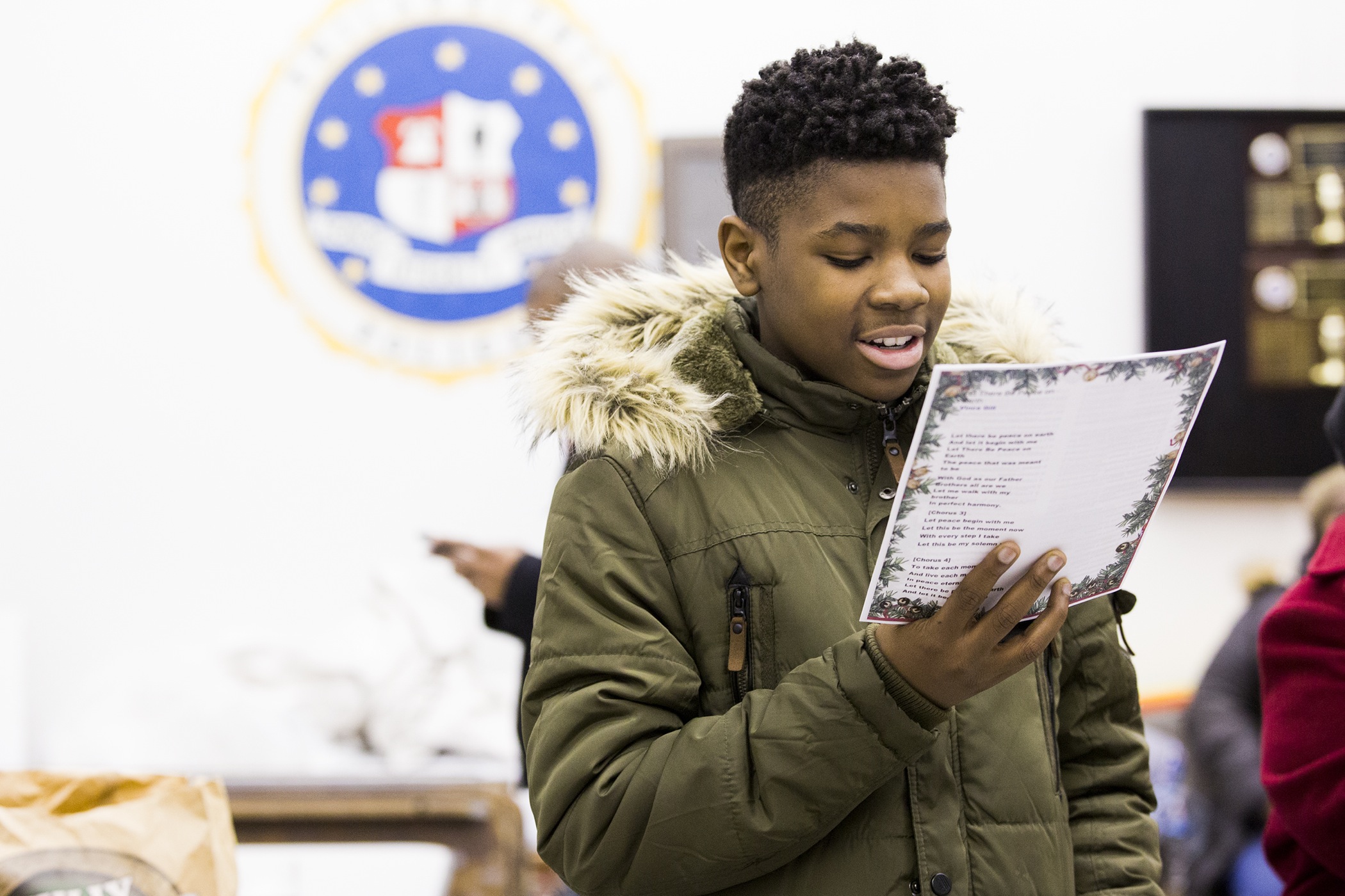 Despite being nervous to interact closely with police officers, Zion Nwalipenja, 13, reads a speech he composed in which he thanks the 39th Police District for attending the caroling event on December 7.