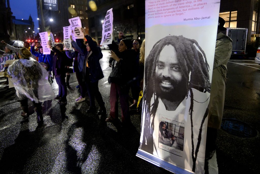 Free Mumia Rally in Philadelphia, PA A group of two dozen activists briefly blocks traffic during a rally outside the Philadelphia district attorney’s office in December. The group is urging District Attorney Larry Krasner not to challenge a Common Pleas Court ruling that allows Mumia Abu-Jamal to file an appeal of his murder conviction. (Bastiaan Slabbers for WHYY)