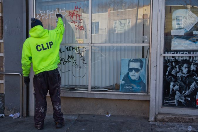 A clip worker removes graffiti around Kensington. (Kimberly Paynter/WHYY)