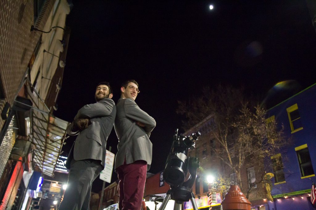 Bill Green (left) and Brendan Happe are amateur astronomers who invite people on the streets of Philadelphia to gaze at the moon through a telescope. (Kimberly Paynter/WHYY)
