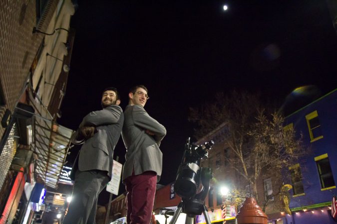 Bill Green (left) and Brendan Happe are amateur astronomers who invite people on the streets of Philadelphia to gaze at the moon through a telescope. (Kimberly Paynter/WHYY)