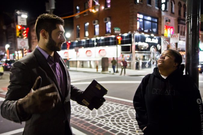 Bill Green (left) dispenses moon facts to revelers at 4th and South Streets. (Kimberly Paynter/WHYY)