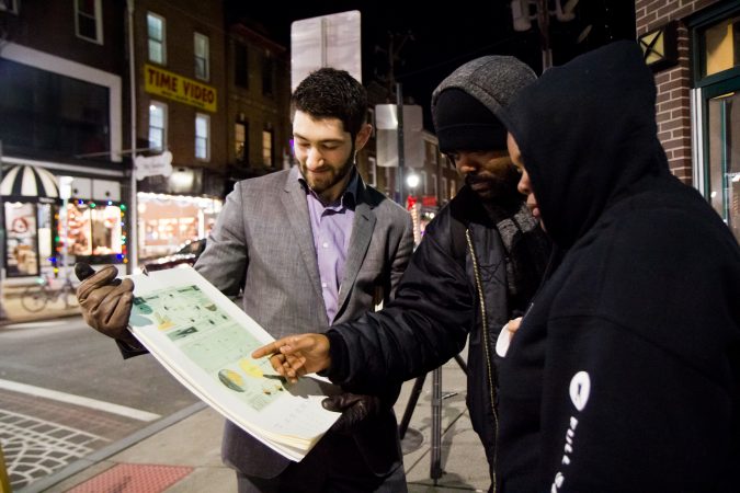 Bill Green (left) dispenses moon facts to revelers at 4th and South Streets. (Kimberly Paynter/WHYY)