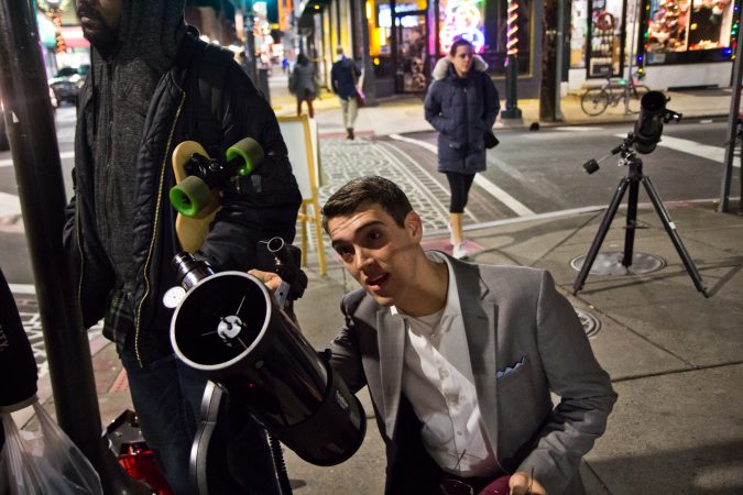 Brendan Happe adjusts the moon gazing telescope at 4th and South Streets in Philadelphia. (Kimberly Paynter/WHYY)