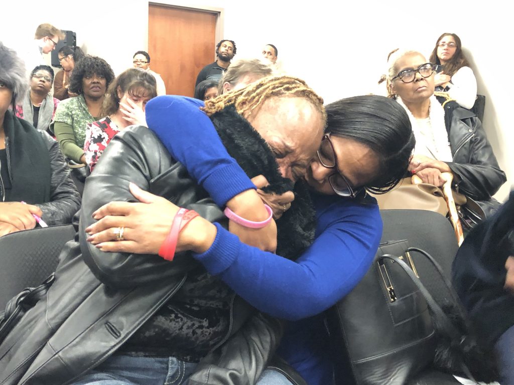 IMG_1144 Sharon Osburn (left) fights back tears after telling prison officials about her son's sudden transfer to a Pennsylvania prison. Osburn is being comforted by state Rep. Sherry Dorsey Walker of Wilmington. (Cris Barrish/WHYY)