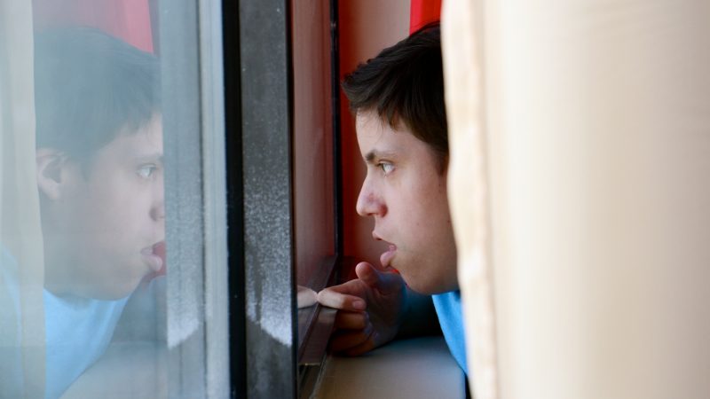 Luis Angel Chaparro Crespo, 16, watches the trains go by from the window of his apartment on the sixth floor of the Harrison Homes in North Philadelphia. He and his parents left Puerto Rico after Hurricane Maria because he needed surgery that could no longer be provided at home. (Emma Lee/WHYY)