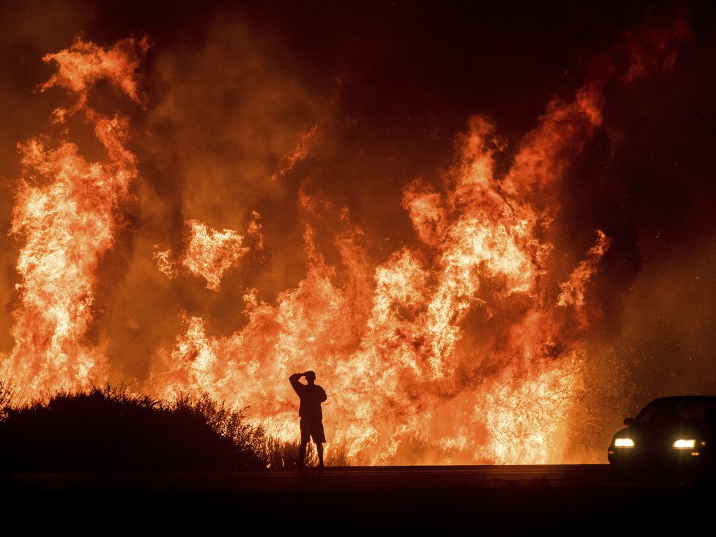 A motorists on Highway 101 watches flames from the Thomas fire leap above the roadway north of Ventura, Calif., in December 2017. Hundreds of homes were destroyed in what was then California’s most destructive wildfire. A motorists on Highway 101 watches flames from the Thomas fire leap above the roadway north of Ventura, Calif., in December 2017. Hundreds of homes were destroyed in what was then California's most destructive wildfire. (Noah Berger/AP)