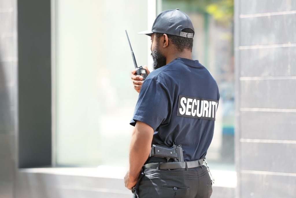 Male security guard using portable radio transmitter outdoors (Yastremska/BigStock)