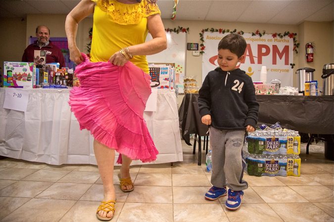 Five-year-old Jose Marlon learns how to dance a traditional dance from Puerto Rico at APM's Three Kings Day/Octavious celebration for diplaced families from Puerto Rico in North Philadelphia on January 12, 2018. (Emily Cohen for WHYY)