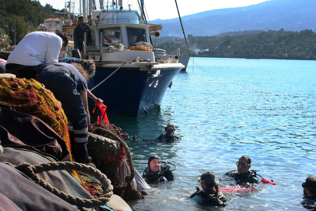 Aegean Rebreath founder George Sarelakos (center) hands a netted bag of marine litter to volunteers on the main pier of the Greek island of Poros. (Joanna Kakissis for NPR)
