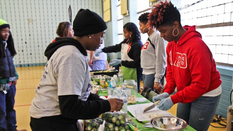 A volunteer at the Vetri Community funds demonstrates healthy cooking at the MLK Day of Service at Girard College. (Kimberly Paynter/WHYY)