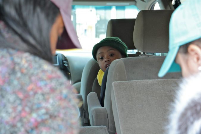 Alora Miller's son, Kevin, watches from his car seat as his mother and her friend, Allyson Bremme, unload donated goods for TSA employees at Philadelphia International Airport. (Emma Lee/WHYY)