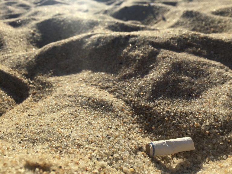 In this Aug. 25, 2018, photo a cigarette butt lies on the sand at  beach in Middletown, N.J. Democratic Gov. Phil Murphy signed the bill banning smoking at the state's public beaches and parks in July, though local communities can opt out and designate small smoking sections. The law takes effect Jan. 16, 2019. (AP Photo/Jenny Kane)