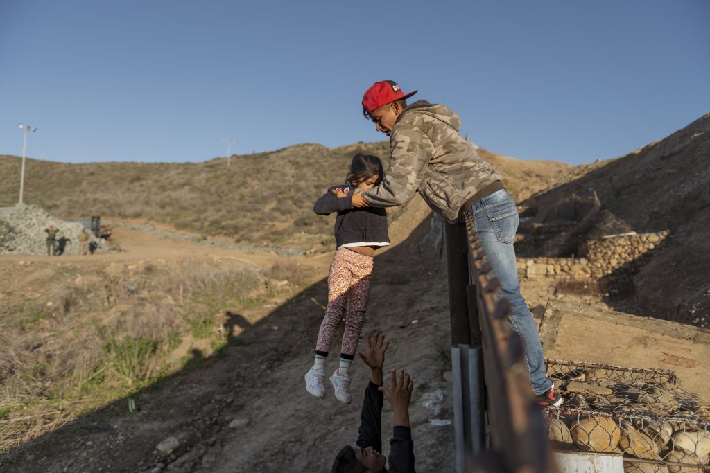 In this Jan. 3, 2019, file photo, a migrant from Honduras pass a child to her father after he jumped the border fence to get into the U.S. side to San Diego, Calif., from Tijuana, Mexico. The Trump administration expects to launch a policy as early as Friday, Jan. 25, that forces people seeking asylum to wait in Mexico while their cases wind through U.S. courts, an official said, marking one of the most significant changes to the immigration system of Donald Trump's presidency. (Daniel Ochoa de Olza, AP Photo)