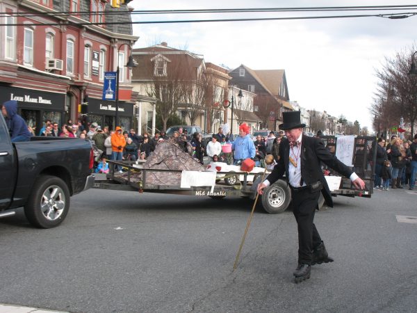 Jack Schreppler still goes around the route on rollerblades. Behind him is a float from Stacey Robinson and friends from Clayton dedicated to the trio who set up the Go Fund Me homeless scam. (John Mussoni/WHYY)