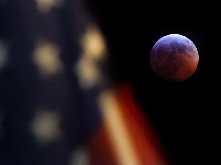 A U.S. flag flies in the foreground of this image of the moon during the lunar eclipse as seen from Washington, D.C., on Sunday night (J. David Ake/AP)