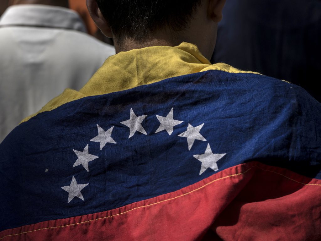 An attendee wears a Venezuelan flag during a rally in Caracas Friday with Juan Guaido, president of the National Assembly, who swore himself in as the leader of Venezuela. An attendee wears a Venezuelan flag during a rally in Caracas Friday with Juan Guaido, president of the National Assembly, who swore himself in as the leader of Venezuela. (Marcelo Perez del Carpio/Bloomberg via Getty Images)