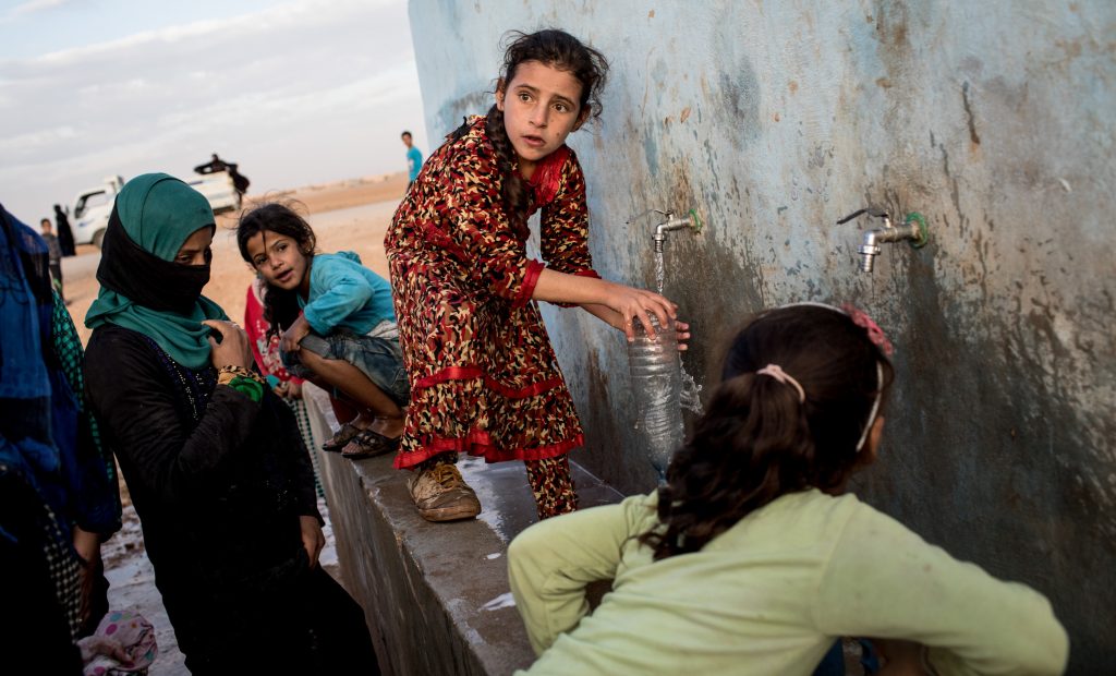 Access to water is increasingly entangled with conflict situations. (Above) A young girl fills a bottle at a pump station at a camp for internally displaced people in Ain Issa, Syria.
(Chris McGrath/Getty Images)