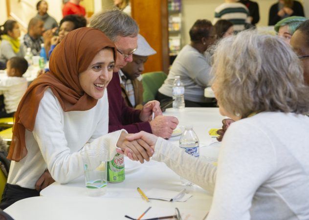Suad Monee introduces herself to a fellow attendee at Uneven Play: A Community Dinner and Conversation held at St Pauls Lutheran Church in Olney. (Jonathan Wilson for WHYY)