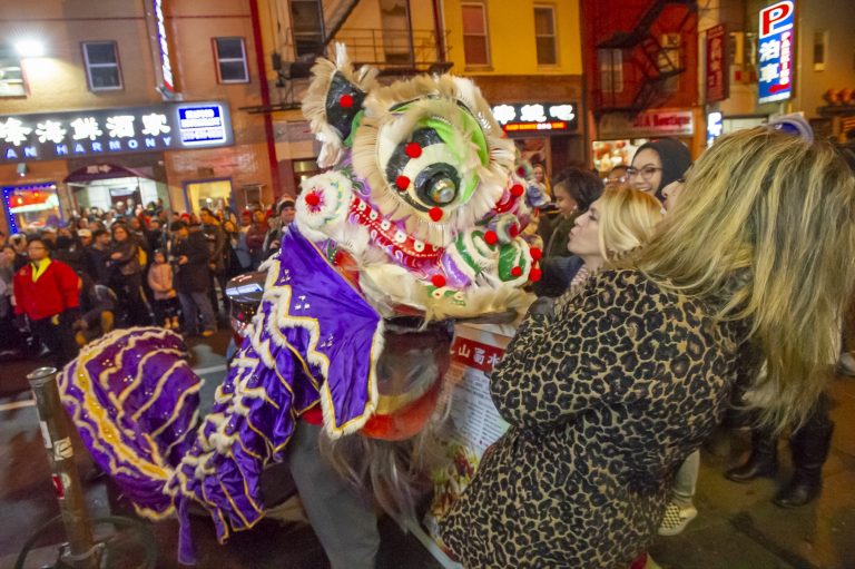 A woman blows a kiss to one of the lions dancing on Race Street during the Chinese New Year celbration. (Jonathan Wilson for WHYY)