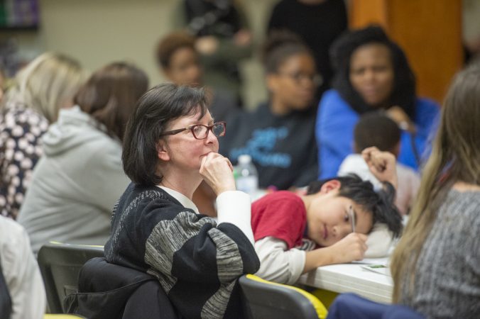 Members of the audience listen to speakers while their children draw pictures during Uneven Play: A Community Dinner and Conversation. (Jonathan Wilson for WHYY)