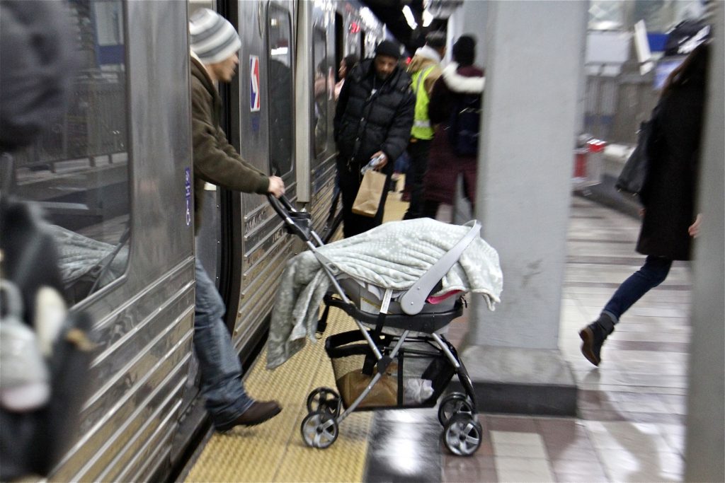 A man pushes a stroller off a SEPTA subway train at the 8th and Market station. (Emma Lee/WHYY)