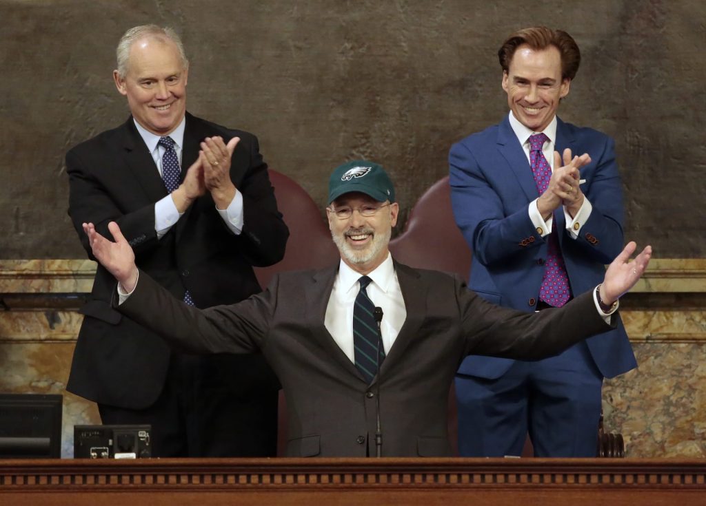 AP_18037646491453-1920×1378 Democratic Gov. Tom Wolf puts on a Philadelphia Eagles hat to celebrate their Super Bowl win before he gives his budget address at the state Capitol in Harrisburg, Pa., on Tuesday, Feb. 6, 2018. (AP Photo/Chris Knight)