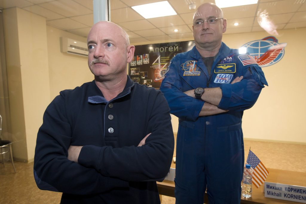 Scott Kelly, Mark Kelly In this March 26, 2015 file photo, U.S. astronaut Scott Kelly, (right), crew member of the mission to the International Space Station, stands behind glass in a quarantine room, behind his brother, Mark Kelly, also an astronaut, after a news conference in the Russian-leased Baikonur, Kazakhstan cosmodrome. Nearly a year in space put Scott Kelly's immune system on high alert and changed the activity of some of his genes compared to his Earth-bound identical twin, according to a report released on Friday, Feb. 15, 2019. (Dmitry Lovetsky/AP Photo)