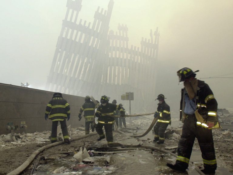 In this Sept. 11, 2001 file photo, with the skeleton of the World Trade Center twin towers in the background, New York City firefighters work amid debris on Cortlandt St. after the terrorist attacks.  (Mark Lennihan/AP Photo, File)