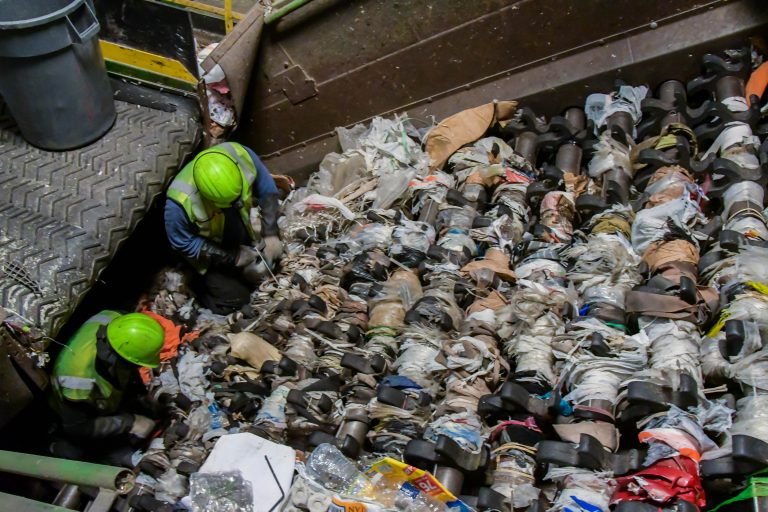 Waste Management technicians clear plastic bags and plastic sheeting from a recycling center screen. Plastic bags and sheeting are a major challenge for recyclers, as they snarl sorting equipment, cause contamination, and drive up processing costs.