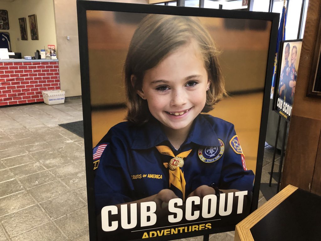 A poster at the entrance of the Laurel Highlands Council headquarters in Pittsburgh shows a young girl in a Cub Scouts uniform. The program for younger kids can include co-ed troops, but older kids will have single-sex troops. A poster at the entrance of the Laurel Highlands Council headquarters in Pittsburgh shows a young girl in a Cub Scouts uniform. The program for younger kids can include co-ed troops, but older kids will have single-sex troops. (Katie Blackley/WESA)